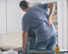 Man bending to the side with hand on hip in pain.