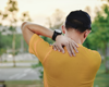 man wearing orange shirt with back pain.