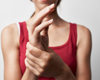 Woman in red tank top holding wrist in pain.