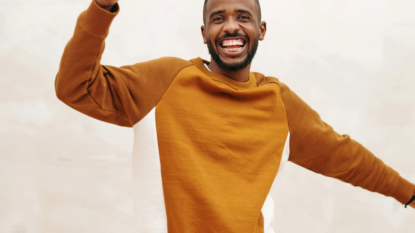 Man in orange sweatshirt cheering with arm in the air.
