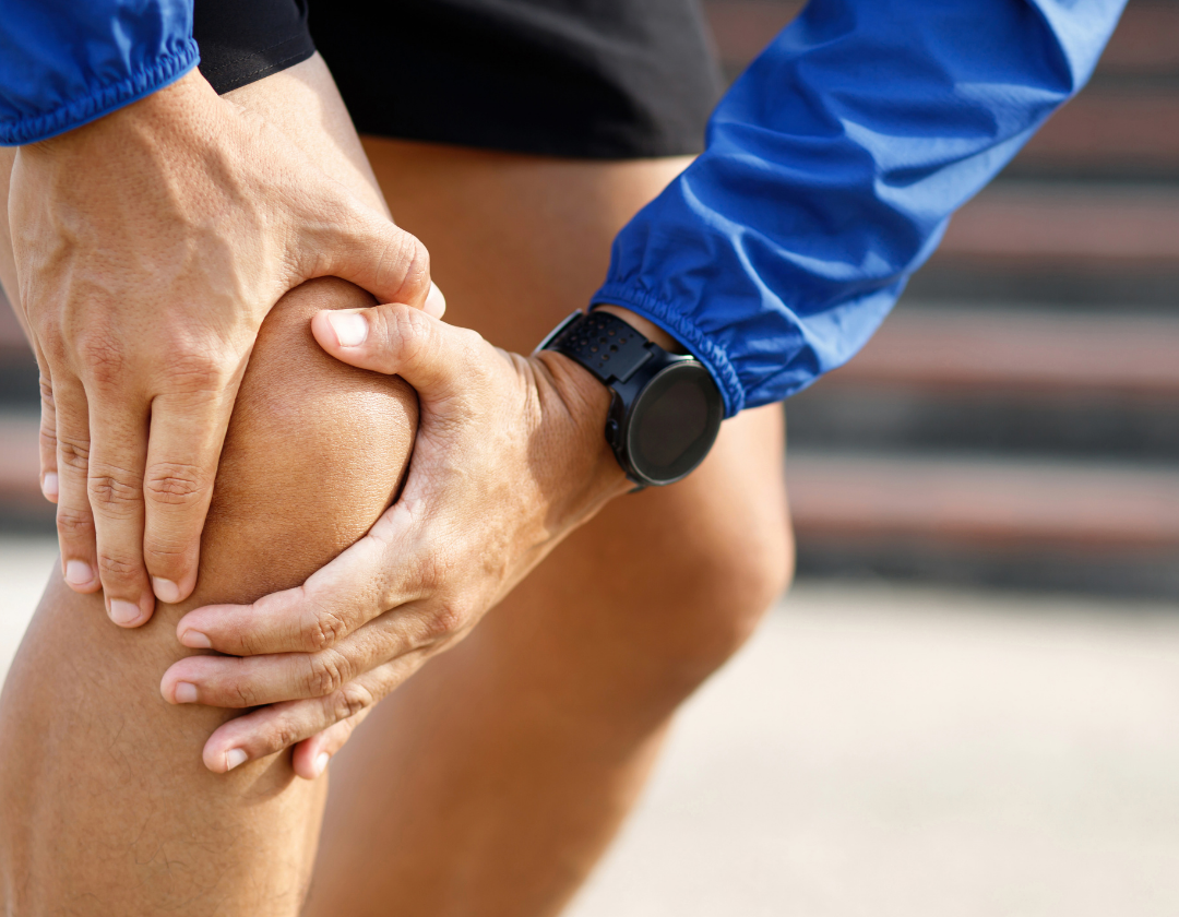 Close up of man in running gear holding knee in pain.