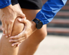 Close up of man in running gear holding knee in pain.
