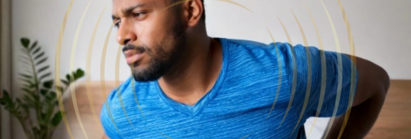 Man in blue t-shirt holding lower back.