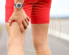 Man in red shorts close up of him holding his upper leg in pain.