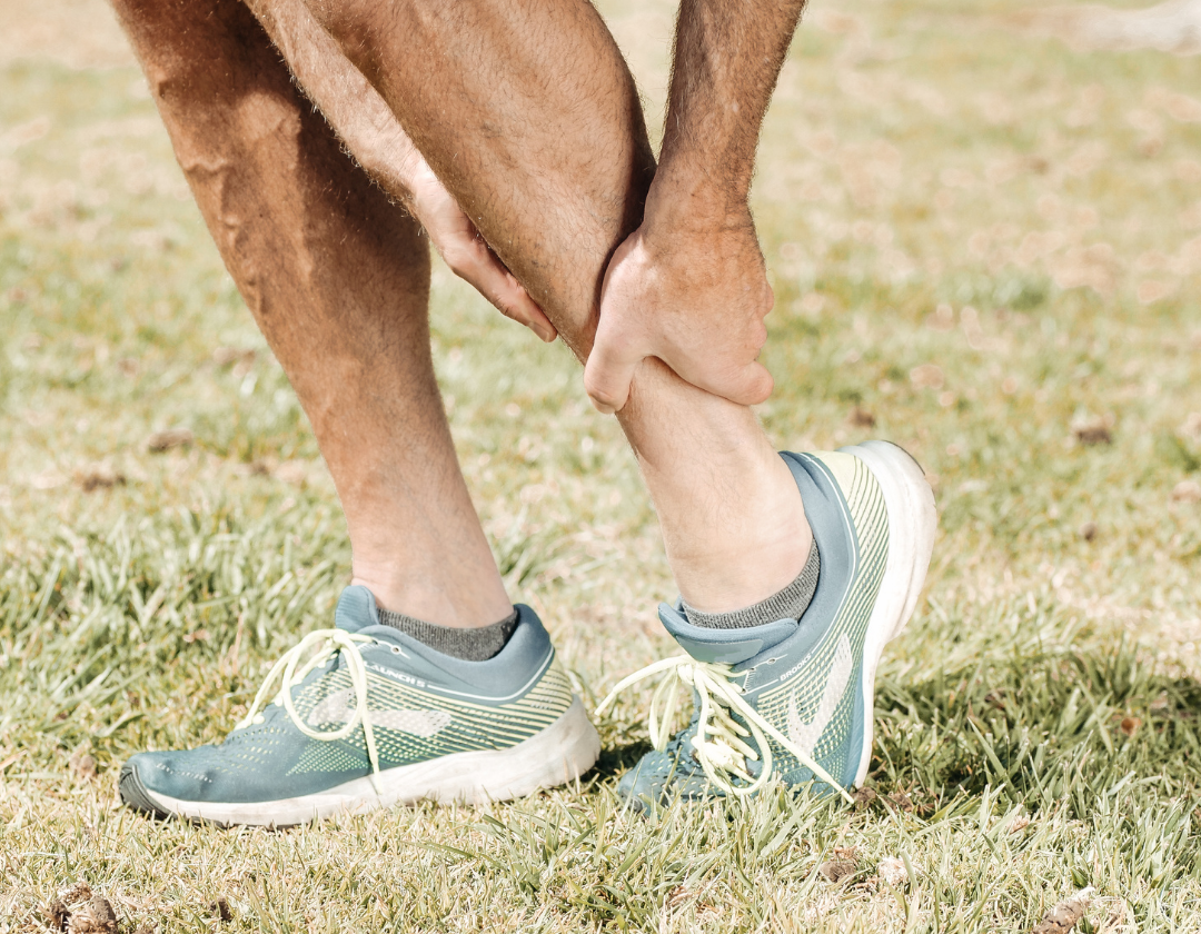 Close up of man in running trainers holding his ancle in pain.