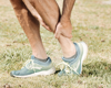 Close up of man in running trainers holding his ancle in pain.