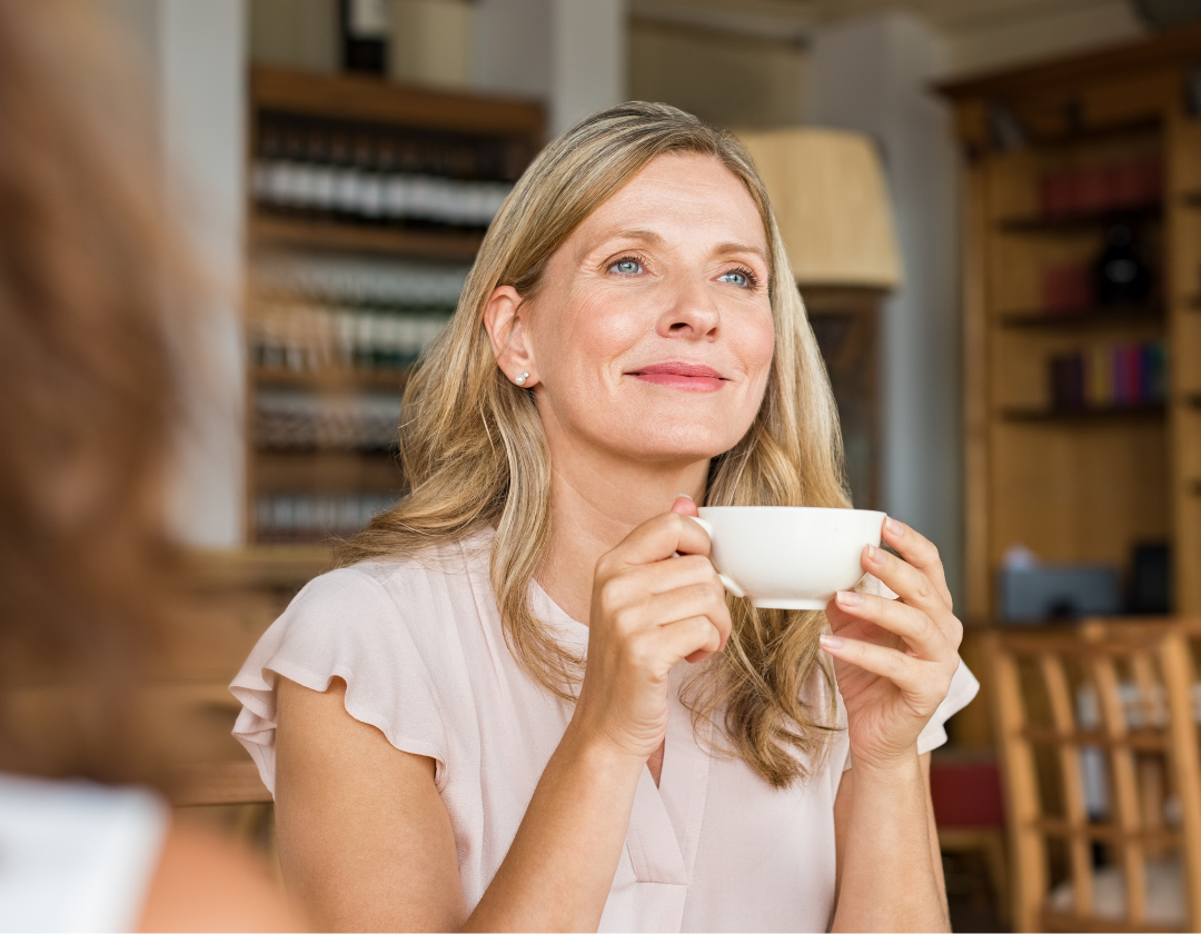 Blonde woman smiling holding cup of tea.