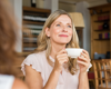 Blonde woman smiling holding cup of tea.