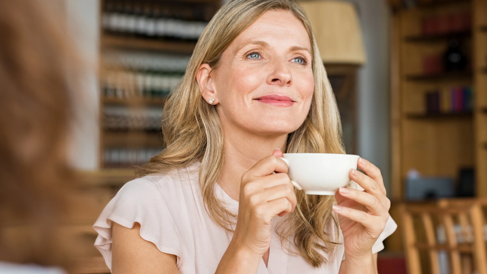 Blonde woman smiling holding cup of tea.
