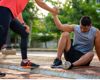 Woman in activewear lifting up a man in activewear off the ground.