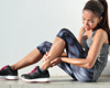 Woman in activewear sat down holding her leg in pain.