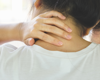 Close up from behind of woman holding her neck in pain.