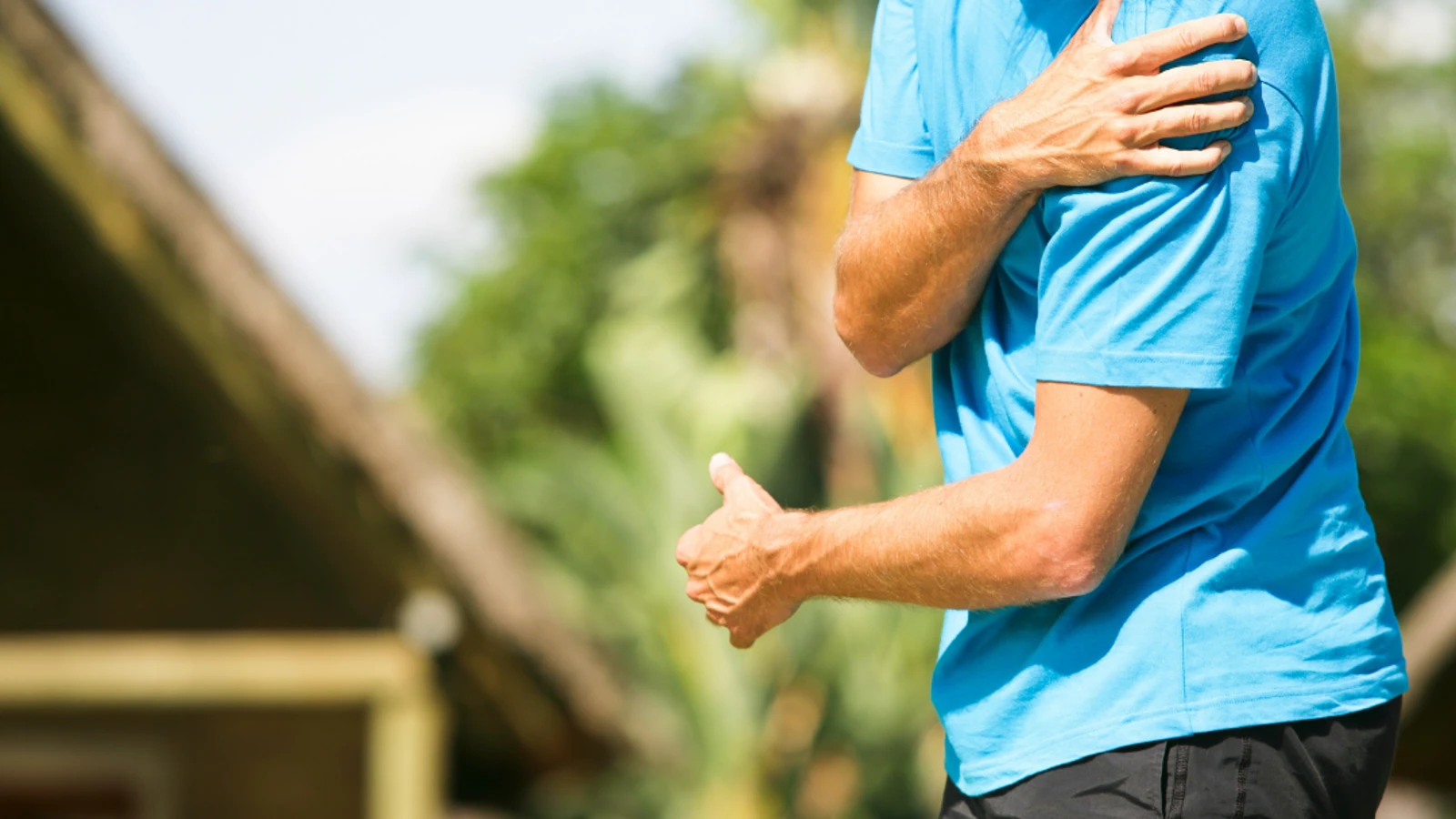 man in running wear holding shoulder