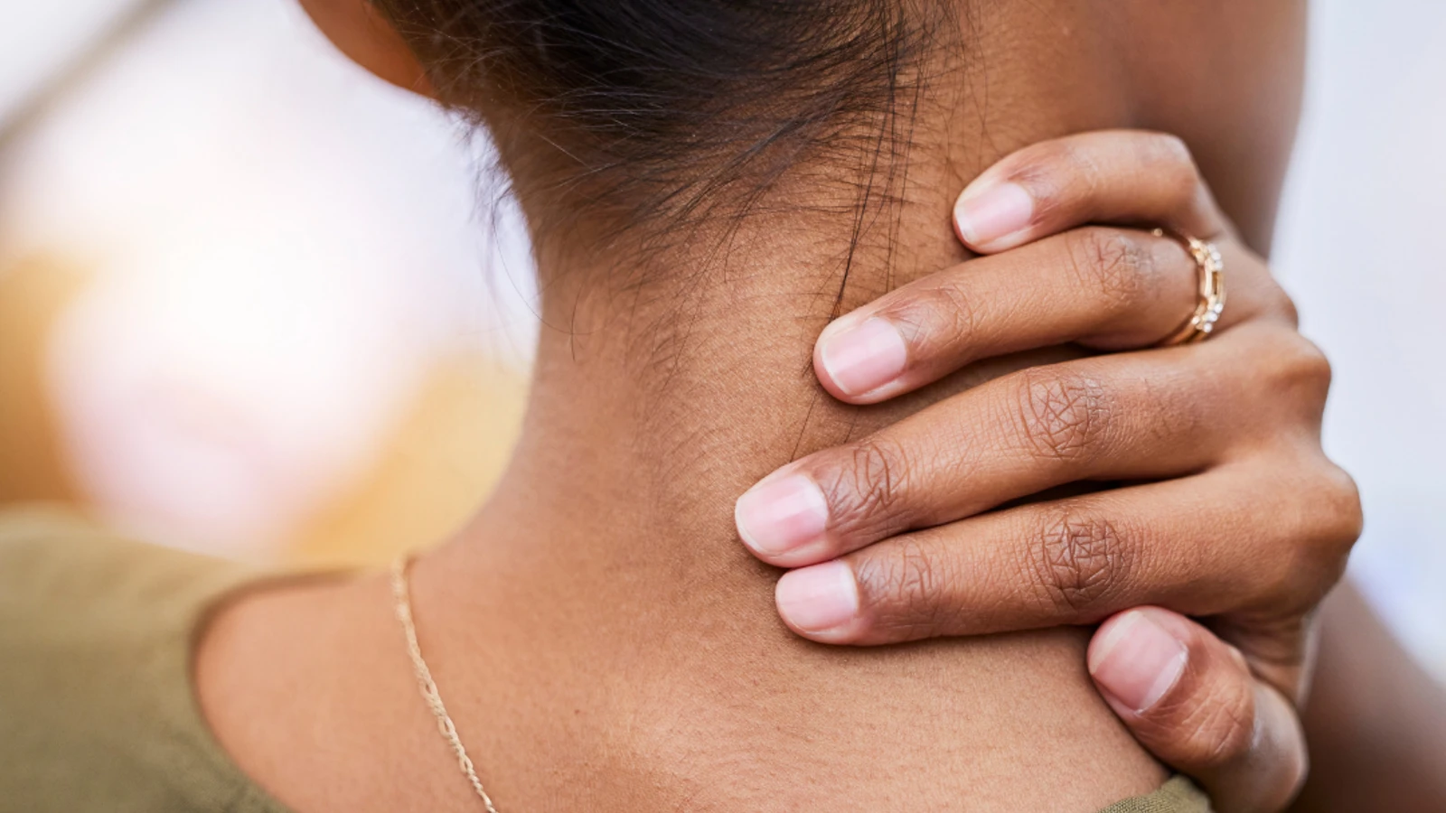 Close up from behind of woman holding her neck in pain.
