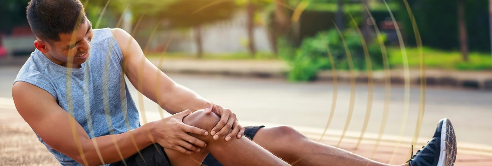 Man in activewear sitting on the flooring holding his knee in pain